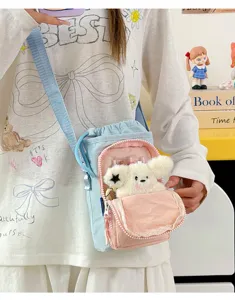 Detail view of lightweight color-block water bottle crossbody bag with cute plush pendant.