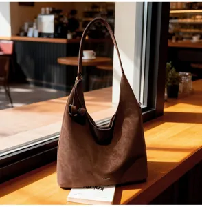 Detail view of brown vintage hobo shoulder bag on wooden cafe counter, soft large capacity.