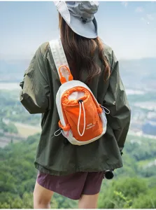 Detailed shot of the casual orange and white colorblock chest bag worn outdoors on a hike.
