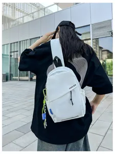 Vue détaillée d'un sac à dos bandoulière blanc décontracté en extérieur, avec sangle et poche.