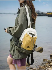 Outdoor detail shot of a stylish color-block sling backpack with drawstring closure.