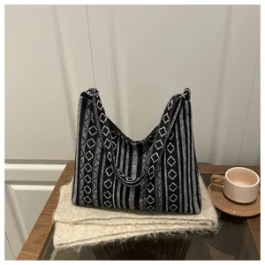 Ethnic style black and white woven fabric shoulder bag detail shot on knitted scarf.