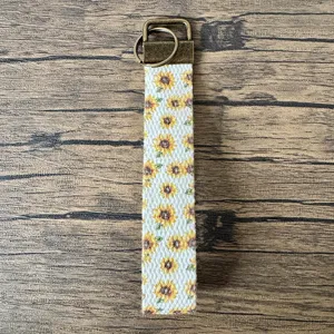 Dettaglio in primo piano del portachiavi da polso stampato con girasole e ferramenta in bronzo.
