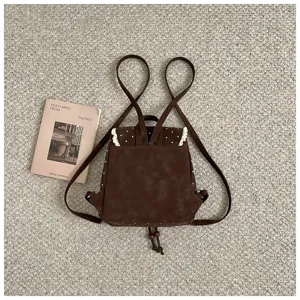 Detail shot of brown vintage mini backpack featuring white polka dots and delicate lace trim.