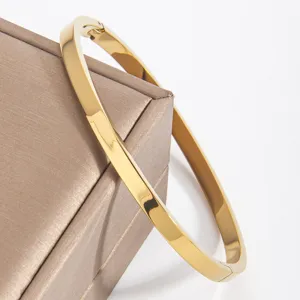 Close-up detail of a smooth minimalist gold stainless steel bangle bracelet on a jewelry box.