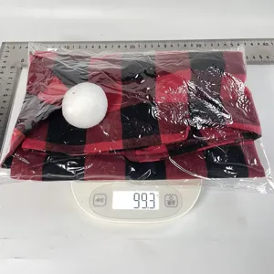 Detail view of red and black plaid Christmas chair cover with white pom-pom decoration.