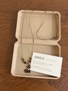 Detailed close-up of vintage Maillard style cat pendant necklace with brown cord and beads.