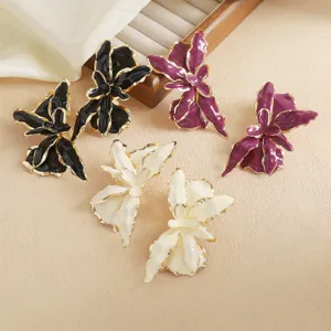Detailed closeup of exaggerated vacation style flower earrings with metal gold edges and vibrant petals.
