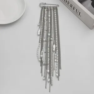 Detailed view of a stylish silver-tone safety pin brooch featuring layered chains and pearls.