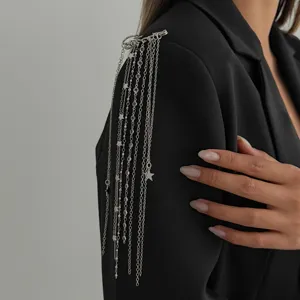 Close-up detail of silver multi-chain tassel brooch with star charms and beads on black blazer.