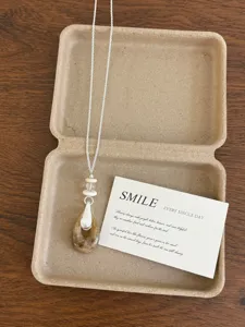 Natural stone teardrop pendant necklace with delicate silver chain in kraft box detail view.