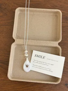 Detailed shot of the elegant long sweater necklace with white resin pendant and delicate chain.