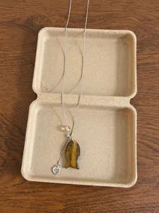 Detailed shot of Korean style tiger's eye stone fish pendant necklace with cute paw charm.