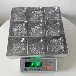 Details von 9 transparenten Weihnachtskugeln mit Silberglitter im Karton auf der Waage.