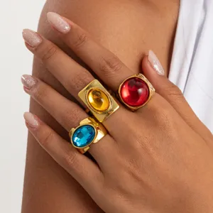 Close-up detail of vintage style chunky gold rings featuring bold colorful gemstone designs.