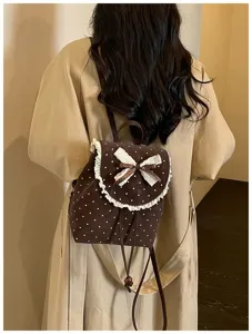 Detailed view of the brown polka dot mini backpack featuring cute lace trim and bow.