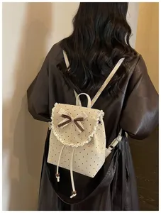 Detailed shot of cute beige polka dot backpack with sweet lace bow on back. Sweet fashion style.