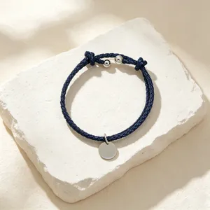 Minimalist dark blue braided leather bracelet with a blank silver round pendant for DIY engraving.