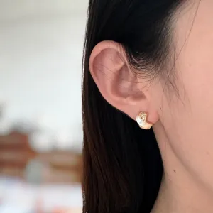 Gros plan détaillé sur les boucles d'oreilles croisées en nacre avec zirconiums.