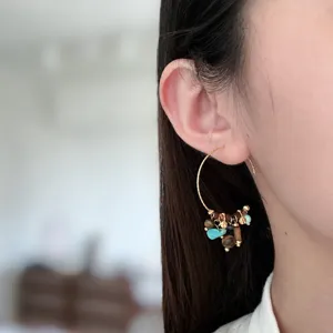 Gros plan de boucles d'oreilles créoles en C avec pampilles, détail délicat et chic.