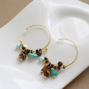 Gros plan de boucles d'oreilles créoles perlées avec turquoise et accents en bois.