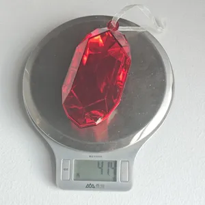 Red faceted acrylic Christmas ornament pendant detailed view on a weighing scale.