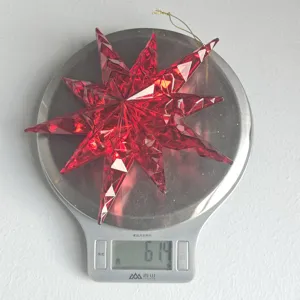 Red faceted acrylic star ornament detail view, shiny Christmas tree hanging decor.
