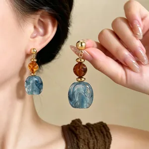 Close-up detail of retro acrylic drop earrings with marble blue beads and gold hardware.