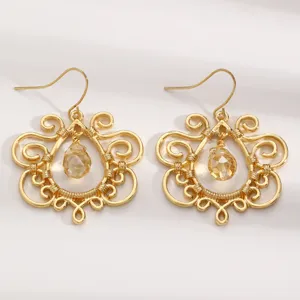 Detailed close-up of vintage gold-plated filigree drop earrings with crystal drops.