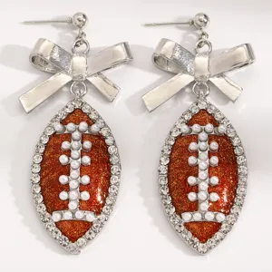 Sparkling football bow earrings with rhinestones and faux pearls for sports fans and party.