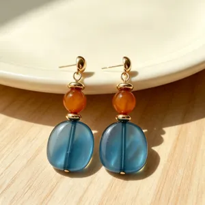Retro drop earrings featuring translucent blue flat beads and orange stones, fine metal detail.