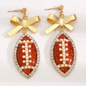 Chic football bow earrings detailed with sparkling rhinestones, pearls and glitter finish.