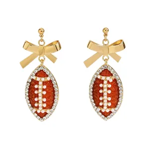 Close-up of sparkling football bow earrings with rhinestones and pearl details for fans.