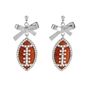 Detailed shot of sparkling football and bow drop earrings with crystal and pearl accents.