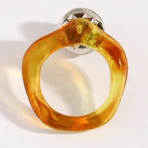 Vue detaillee d'une broche en resine ambre, accessoire elegant pour lunettes de soleil mode.