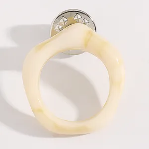Vue detaillee de la broche lunettes en resine creme creative, accessoire de costume elegant.