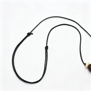 Vista detallada del collar de cordón negro ajustable con cuenta de madera y colgante étnico.