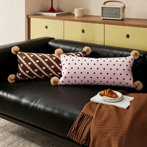 Vue détaillée de coussins longs et confortables avec motifs cœurs et pois sur le canapé.