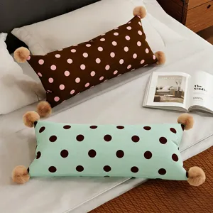 Gros plan détaillé de longs coussins moelleux avec des pompons mignons et des pois.