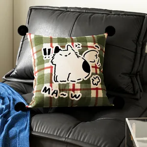 Green and red plaid decorative pillow with cute cartoon cat graphic and black pom poms.