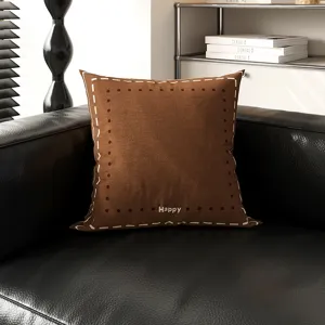 Detailaufnahme des braunen Dopamin-Quadratkissen mit Keksmuster auf schwarzem Ledersofa.
