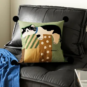Detail view of a cute cartoon cat cushion pillow with pom-pom corners for living room sofa.