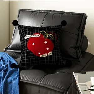 Black grid throw pillow with red apple embroidery and pom poms detail for living room couch.