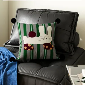 Green decorative throw pillow featuring cute cartoon rabbit and apple design for sofa.