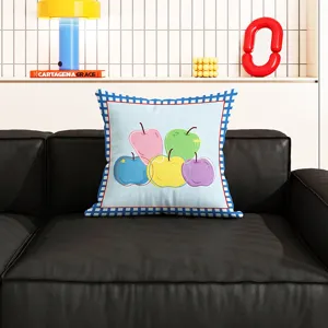 Detailansicht eines bunten Kissen mit Apfelmuster auf einem modernen schwarzen Ledersofa.