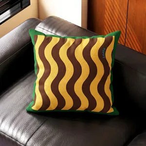 Vista detallada del cojin geometrico retro con patron ondulado y borde verde en el sofa.