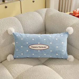 Close-up detail of blue polka dot throw pillow featuring white pom-poms for cozy sofa decor.