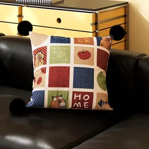 Charming capybara throw pillow with black pom poms, grid patchwork cushion detail for sofa.