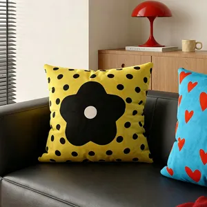 Fodera per cuscino gialla a pois neri con fiore, perfetta per divano in stile moderno.