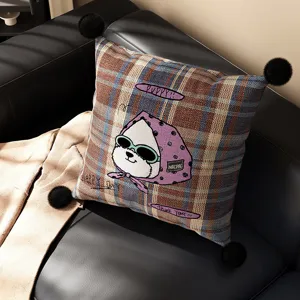 Detailed view of British plaid throw pillow featuring cute cartoon animal design and pom-poms.